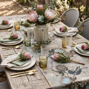 Powder Protea table runner on a garden table set with pink proteas, gold cutlery and sage napkins